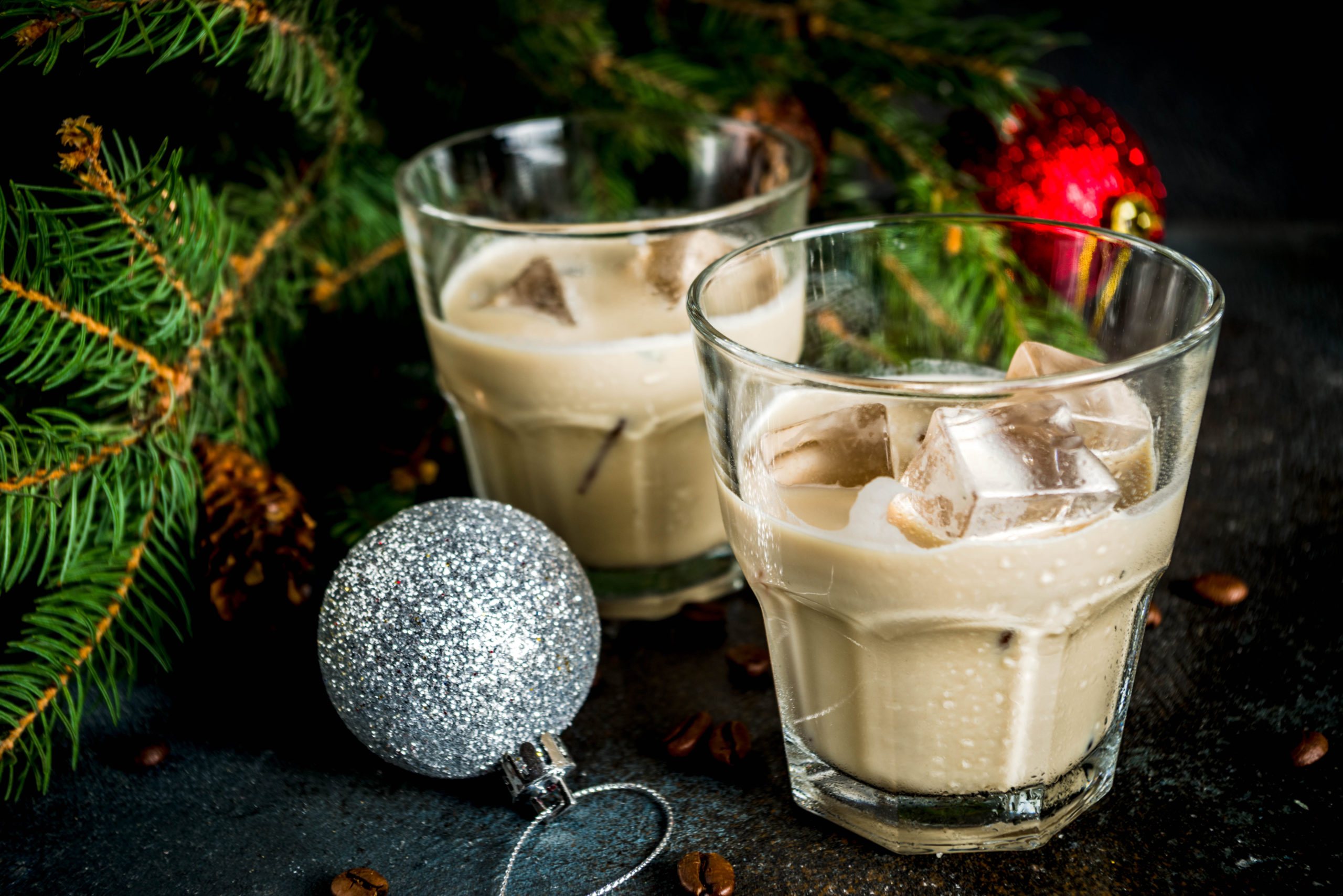 Irish cream cocktail or liqueur, traditional winter christmas drink, dark rusty background with fir tree branches, coffee beans and christmas decorations, copy space