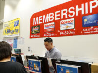 A man standing at the cash register in a Costco store in front of a sign about memberships.