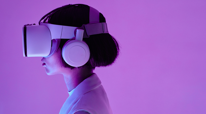 An image of a woman with black hair wearing a virtual reality headset against a purple background