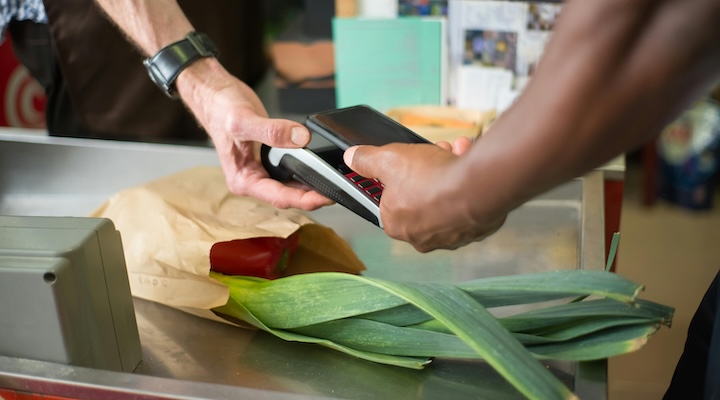 Close-up of customer paying for grcoeries using efrtpos machine