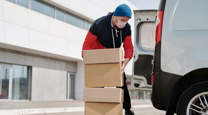 Delivery man wearing a face mask carrying boxes