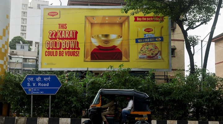 An auto-rickshaw drives past a hoarding promoting Nestle Maggi 2-Minute Noodles