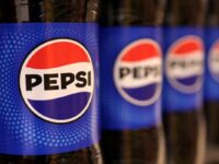 Bottles of Pepsi are displayed on a shelf in a supermarket